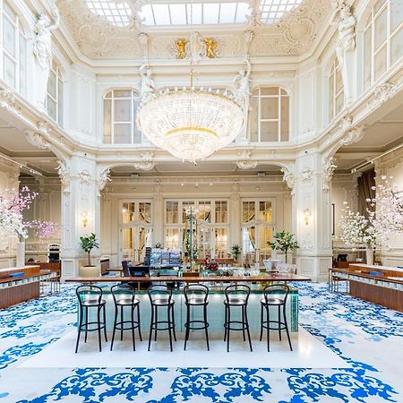 Grandhotel Pupp Karlovy Vary Ngoại thất bức ảnh The photo shows an elegant interior space, likely a hotel lobby or a high-end establishment. The room features high ceilings adorned with ornate moldings and a large chandelier that hangs prominently from the ceiling. The space is filled with natural