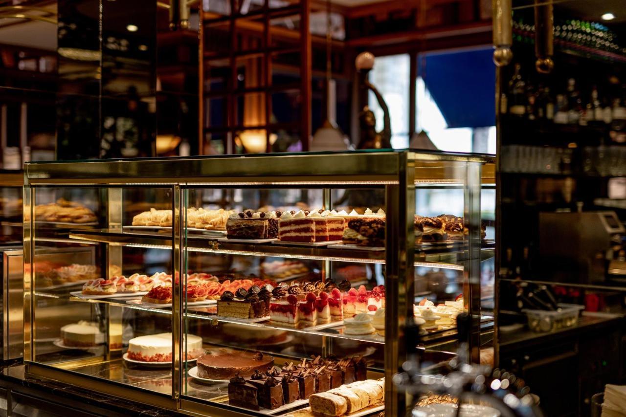 Grandhotel Pupp Karlovy Vary Ngoại thất bức ảnh The photo displays a beautifully organized glass display case filled with an assortment of pastries and cakes. There are various types of desserts, including layered cakes, chocolate treats, and fruit-topped confections. The setting appears to be a c
