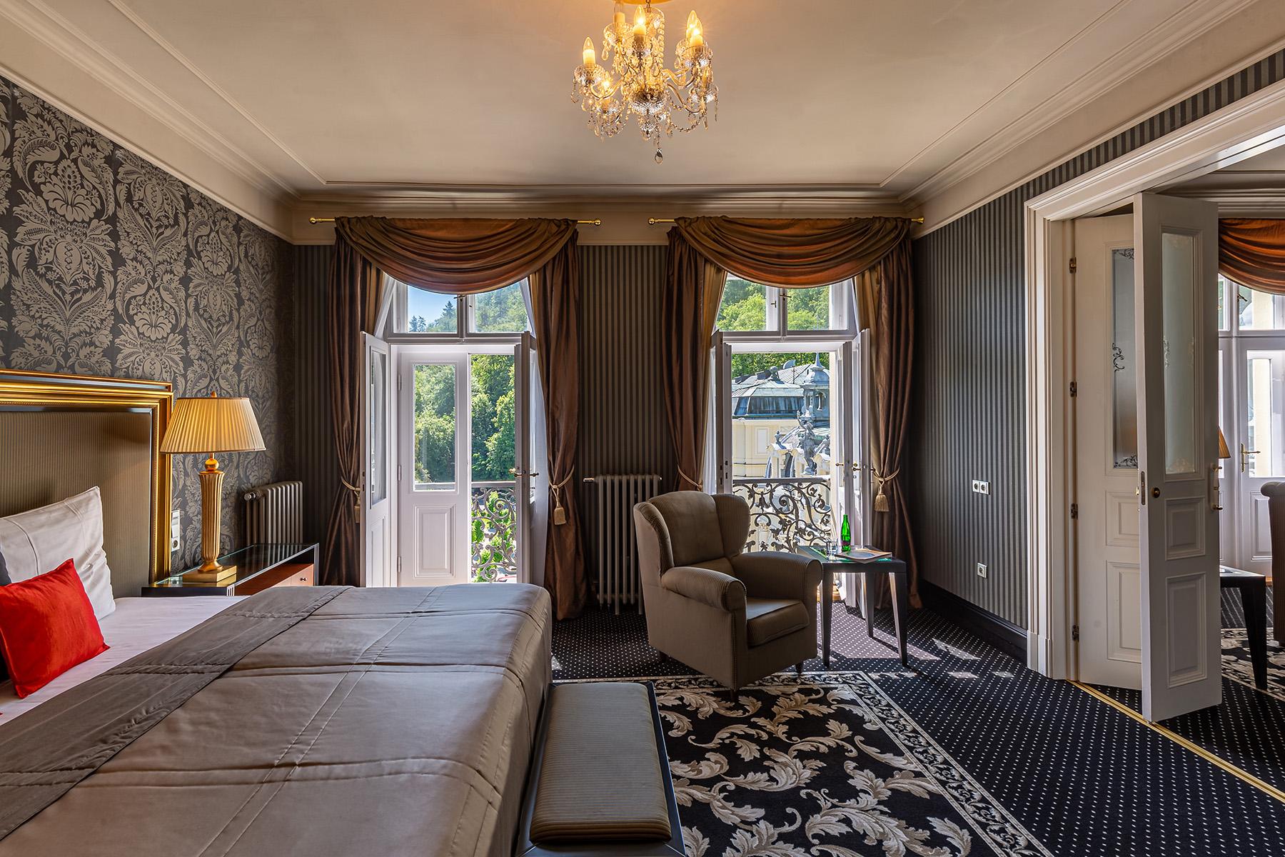 Grandhotel Pupp Karlovy Vary Ngoại thất bức ảnh The photo shows a beautifully decorated hotel room or suite. It features a large bed with a stylish headboard and luxurious bedding. The walls are adorned with elegant wallpaper, and there are draped curtains framing two large windows that let in nat